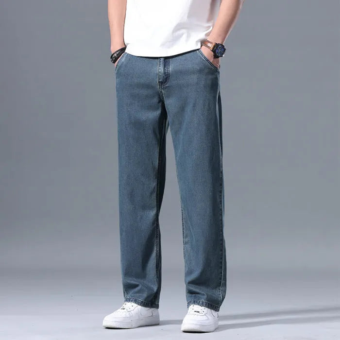 Man wearing light blue loose straight-leg lyocell jeans on a casual background.