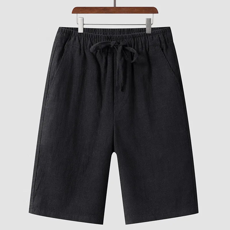 Men's beige linen casual shorts with a loose fit and cropped length on a plain background.