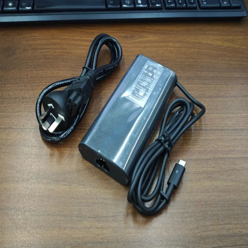 Black 65W USB-C laptop power adapter with a set of international plug cords for UK, US, EU, AU and SA sockets.