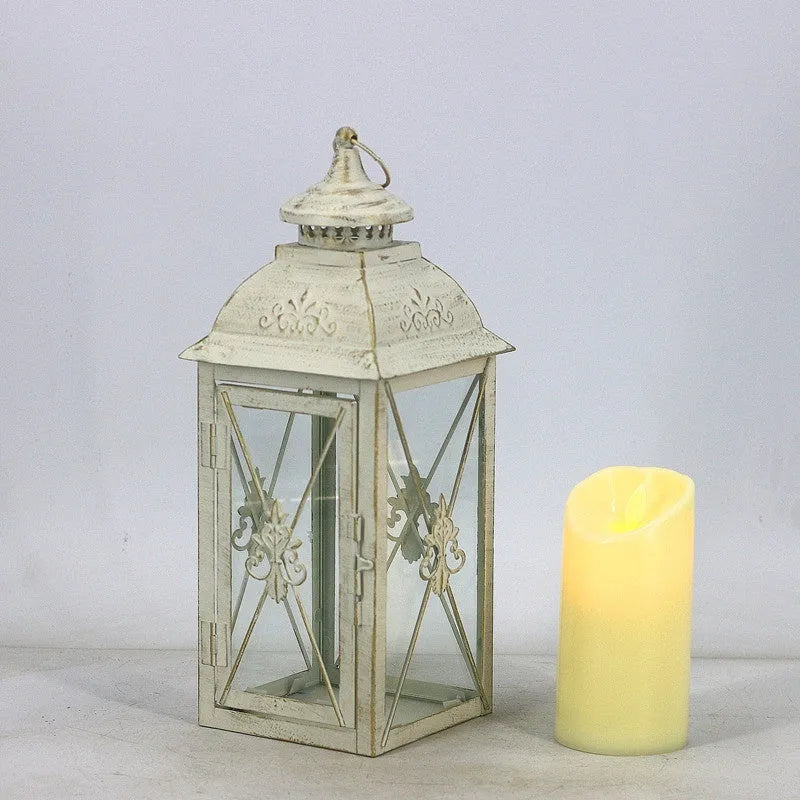 Black wrought iron floor lantern with glass panels on a stone patio.