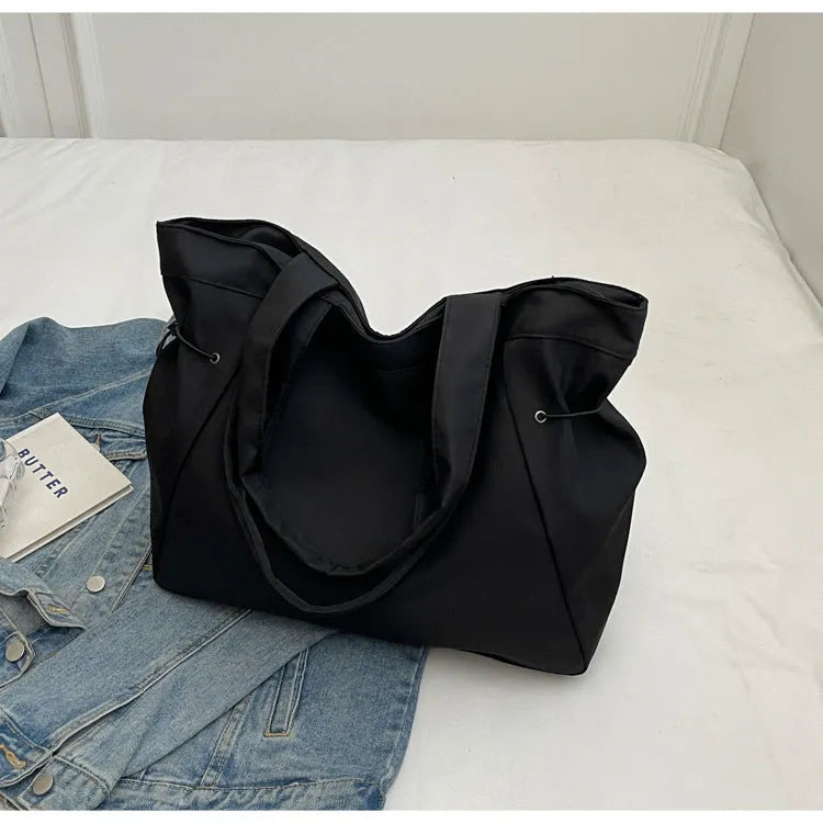 Soft folding shoulder tote bag in Oxford cloth shown in one of five colour options: black, brown, dark grey, light grey, or purple.