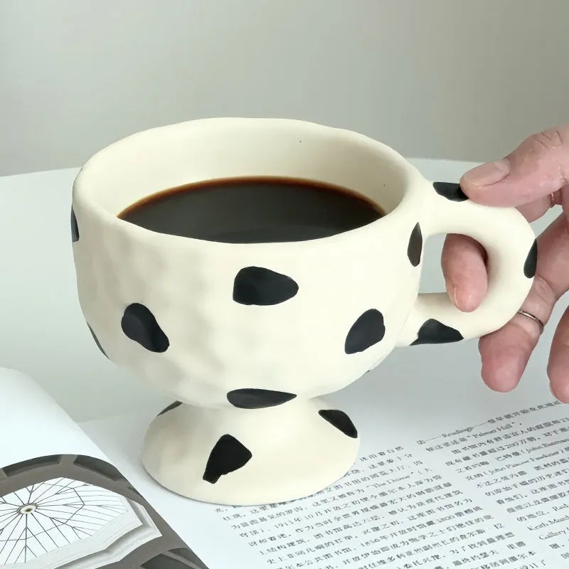 Hand-pinched irregular shaped ceramic mug in a solid colour on a table.