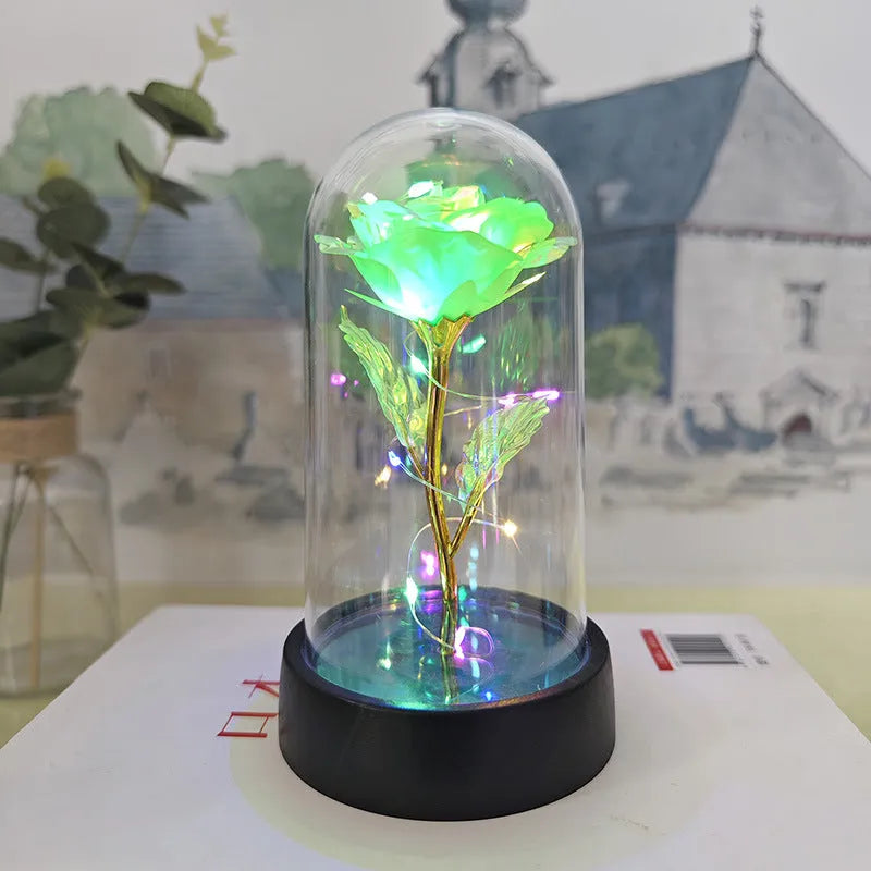 Small decorative table lamp with coloured LED lights illuminating plastic flowers under a glass dome.