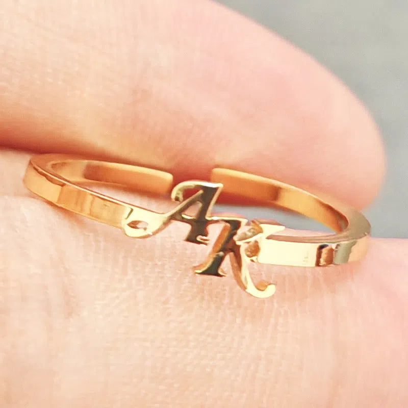 Customised two-letter open ring in stainless steel silver and gold electroplated finish on a white background