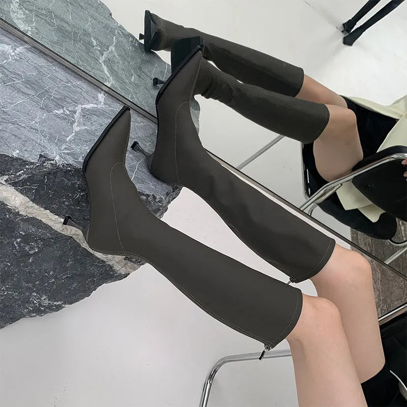 Women's black pointed toe stiletto heel boots with a back zipper, shown below the knee.