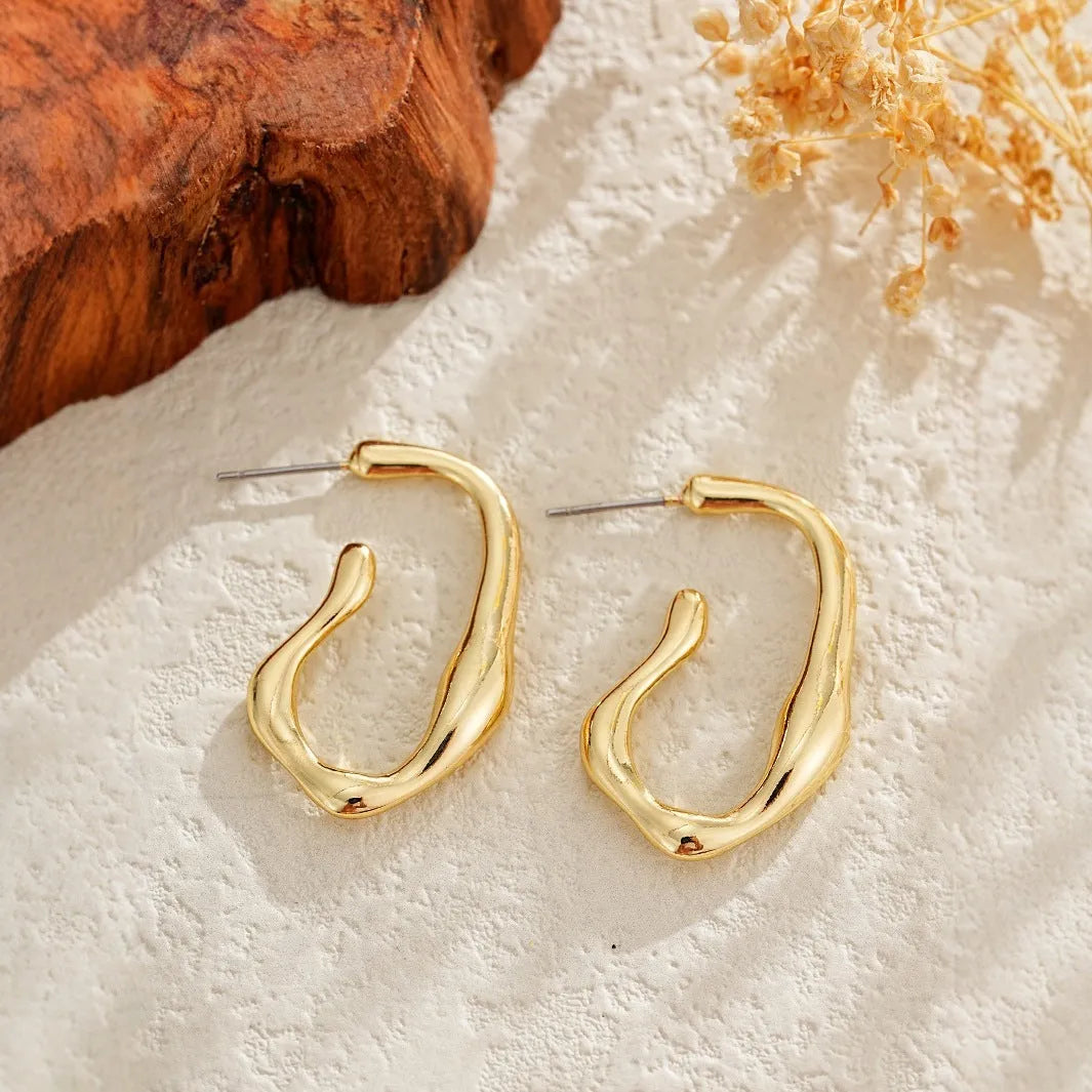 Irregular shaped minimalist gold dangle earrings for women on white background