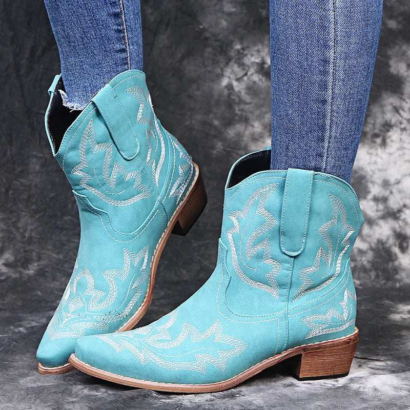 Blue women's cowboy boots with embroidery and a low wedge heel on a wooden floor.