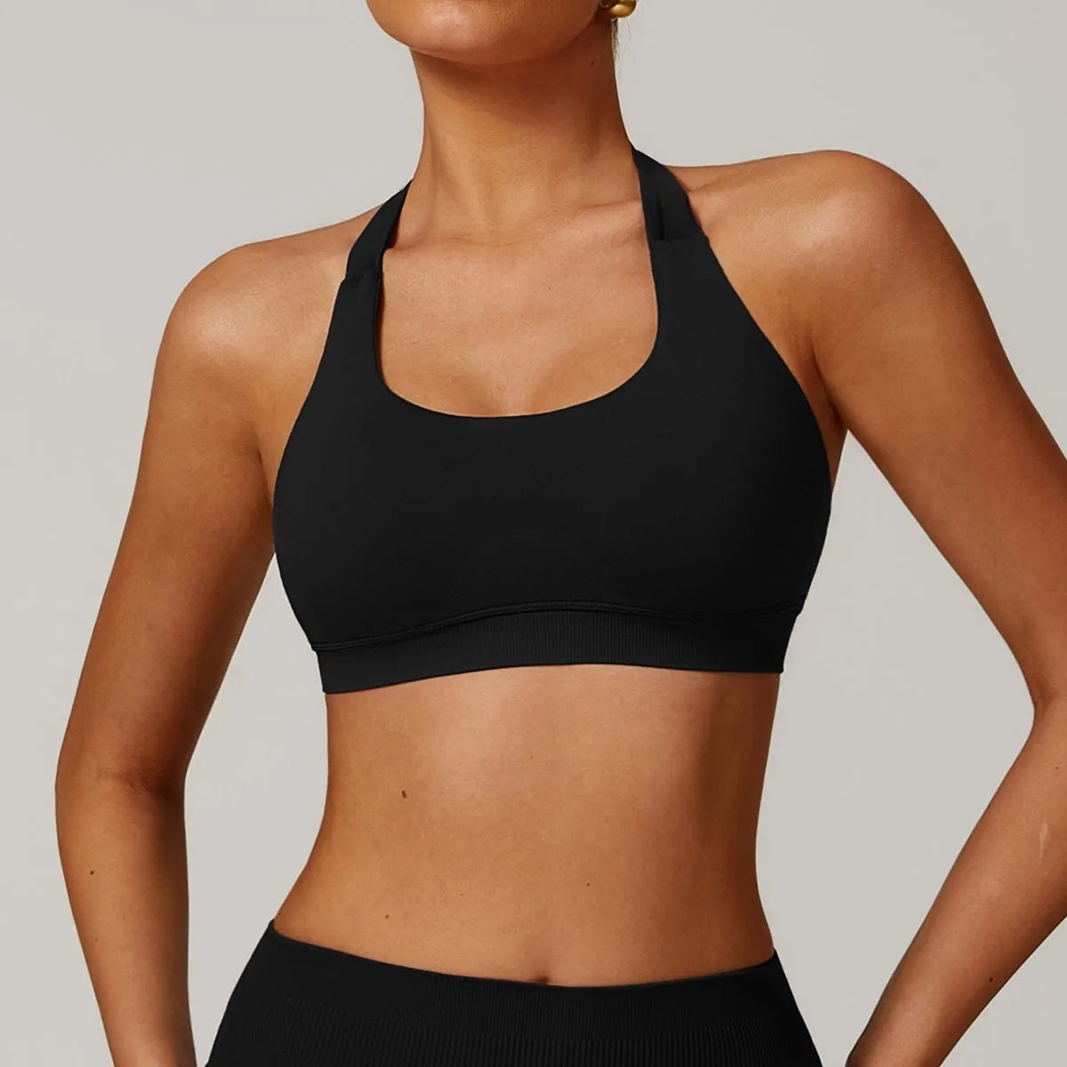 Women's black halter neck sports bra with medium support and hollow back.