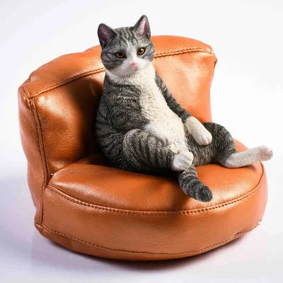 Small lazy cat car ornament and sofa, 7.5cm tall resin model on a car dashboard.