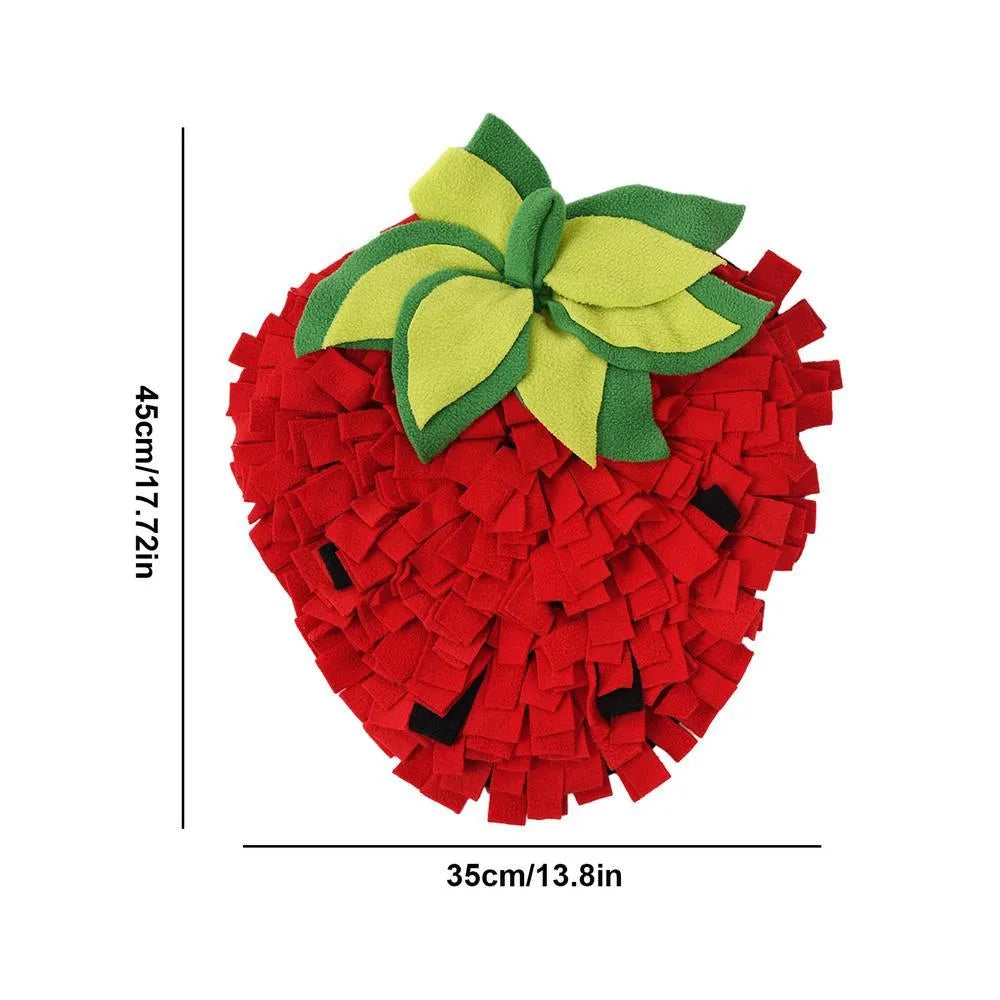 Red and green strawberry-shaped snuffle mat for dogs and cats on a floor.