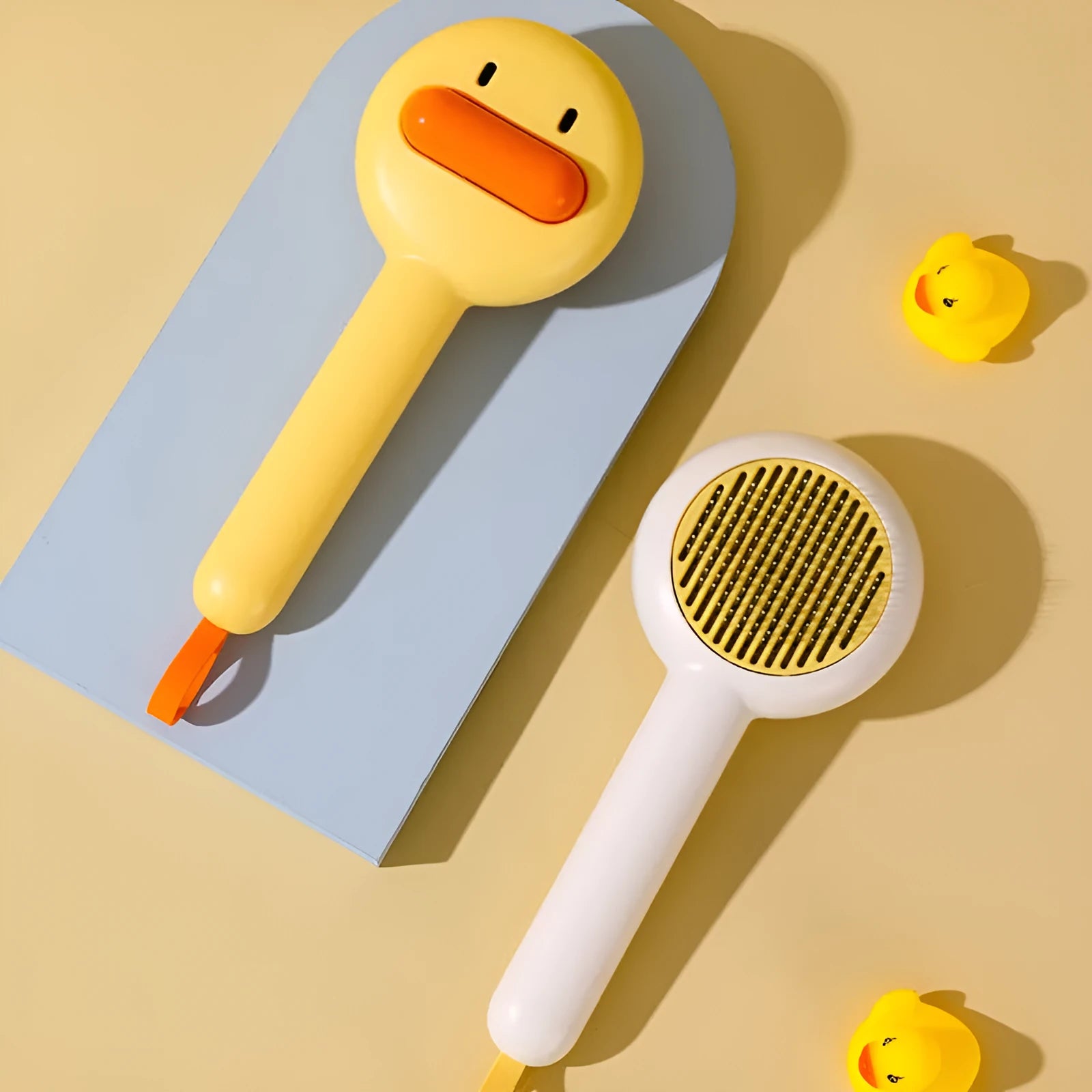 Small yellow plastic duck-shaped pet grooming comb with needle bristles.
