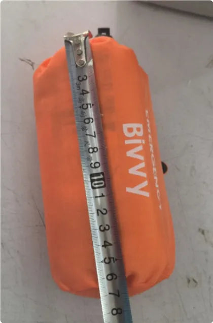 Orange emergency relief tent with sleeping bag and raincoat in temporary outdoor shelter setup