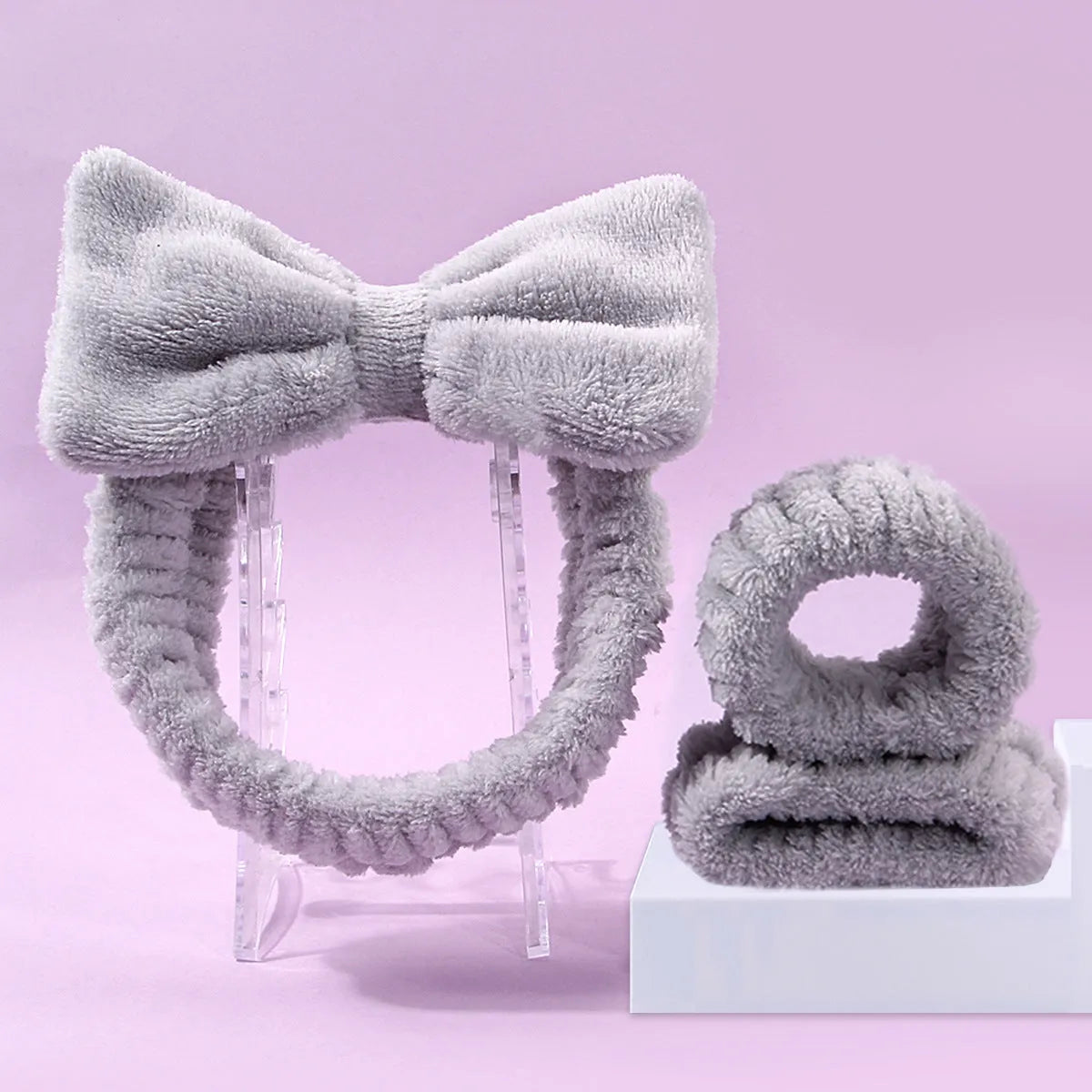Facial brush with plastic handle and nylon bristles alongside coral fleece absorbent hair band in purple colour