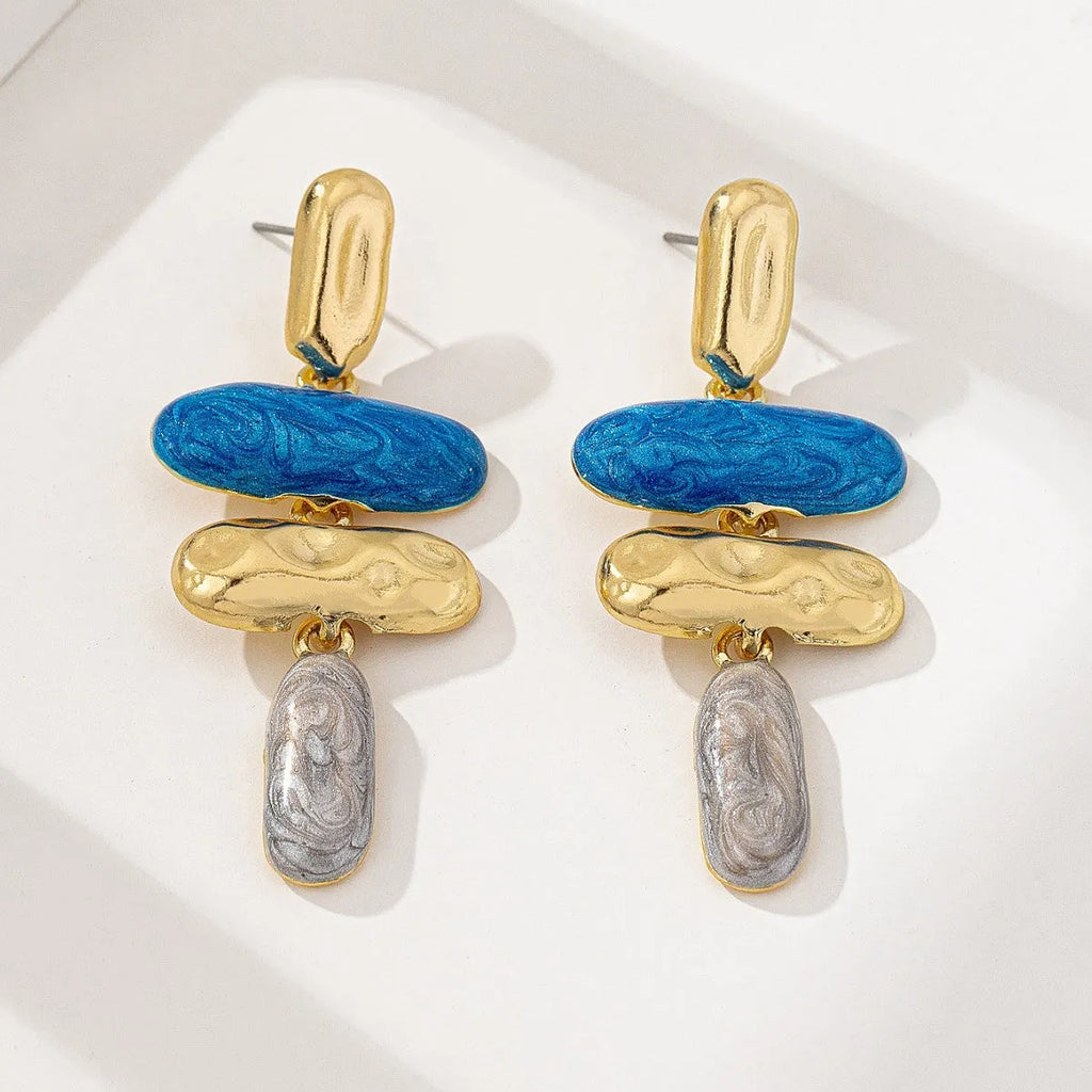 A pair of simple geometric stud earrings with a multicolour electroplated finish on a white background.