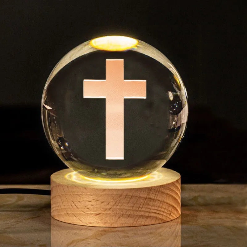 White crystal ball ornament on wood base with warm light and religious symbols