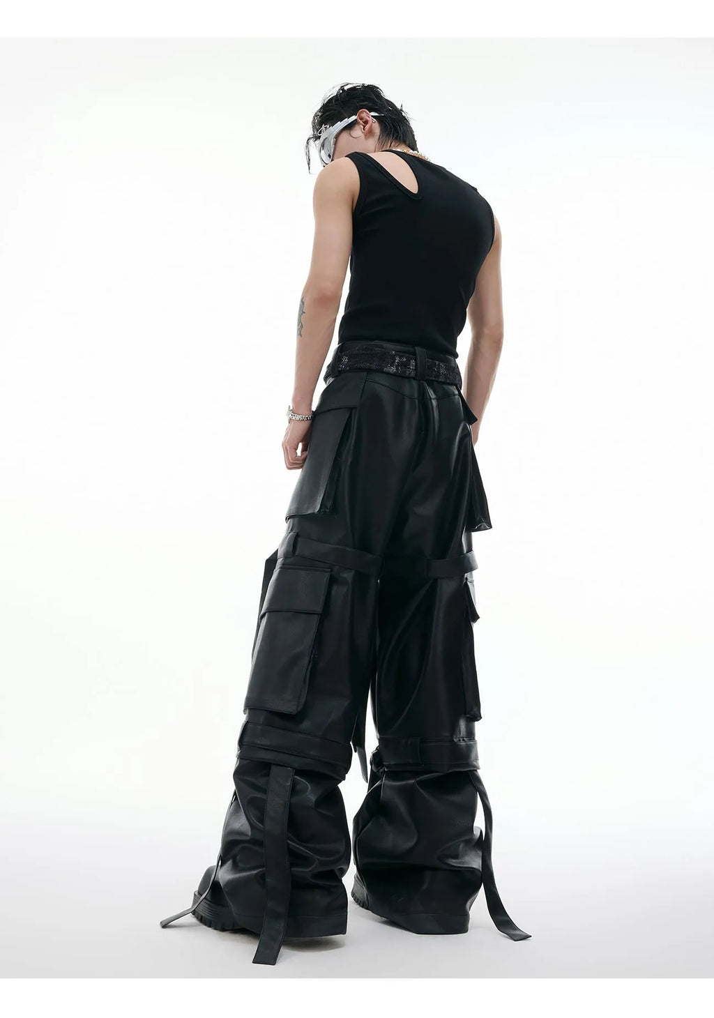 Black loose-fit men's trousers with multiple pockets, quilted panels, and decorative leather ribbon trim.
