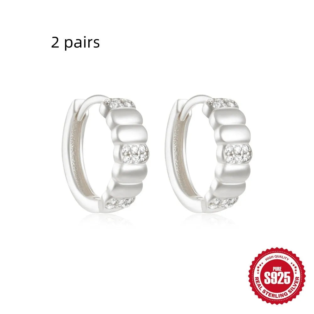 A pair of small, round, geometric stud earrings made of sterling silver with an electroplated finish.