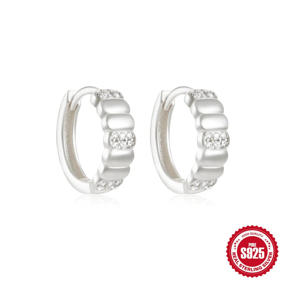 A pair of small, round, geometric stud earrings made of sterling silver with an electroplated finish.