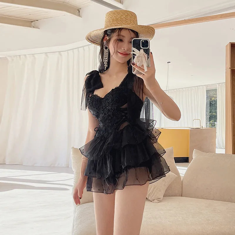 Black one-piece swimsuit with gathered chest detail on a mannequin, showing conservative sleeveless design.