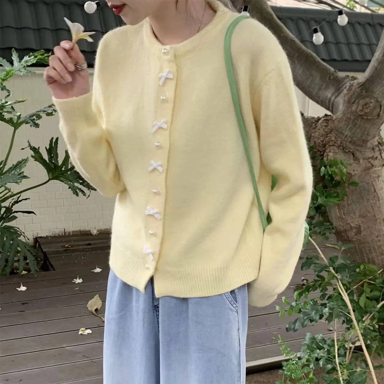 Women's solid colour cardigan sweater with bow and pearl button design in medium thickness fabric