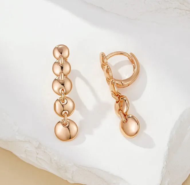 A pair of long, round, gold-toned retro earrings with a woven copper design.