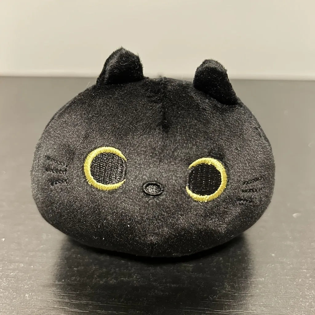 Black fluffy cat plush toy with printed face, sitting upright as a soft cushion.