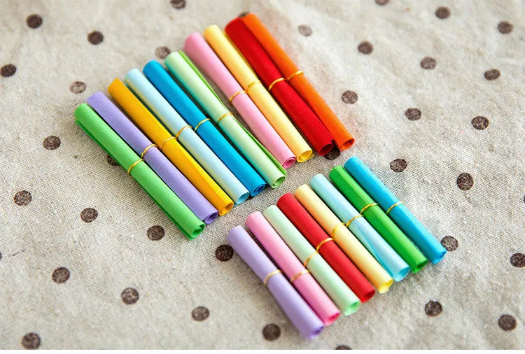 Assorted coloured miniature paper scrolls for drift bottle messages, showing pre-punched hole.
