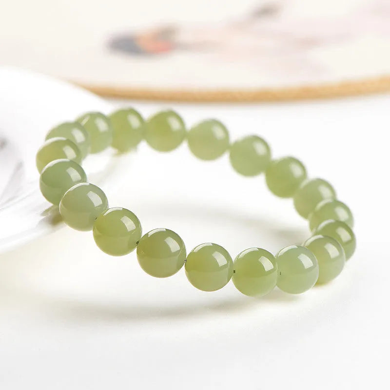 Polished Hetian jade bead bracelet in clear ice-like colours on a white background.