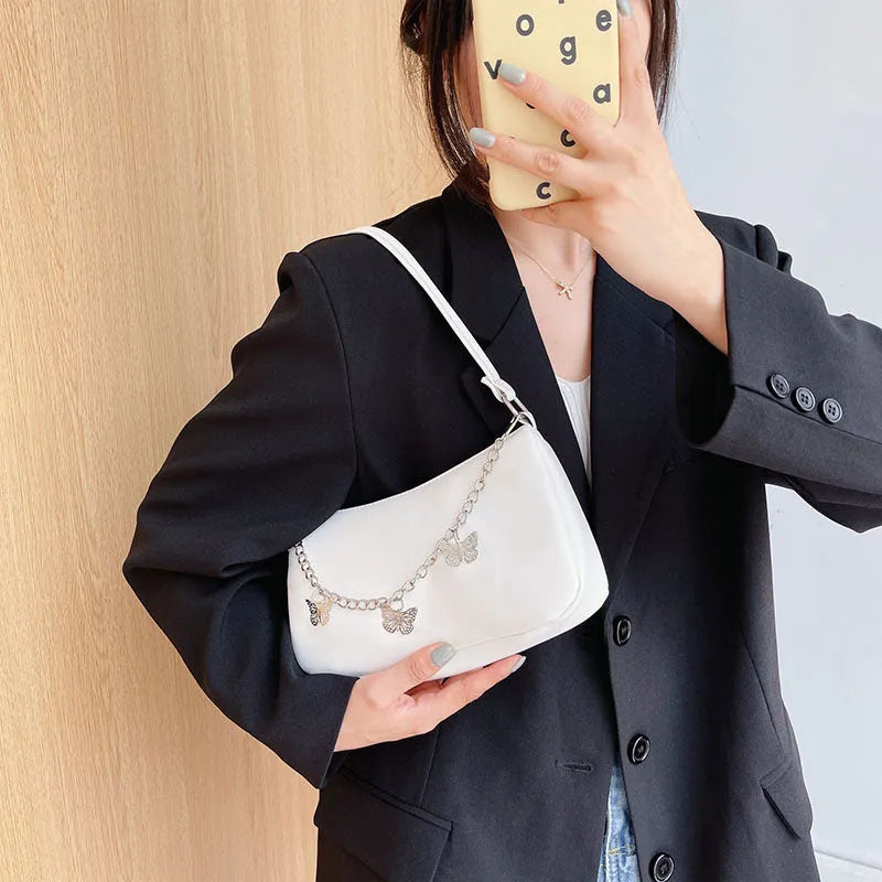 Women's black PU leather crossbody bag with butterfly chain shoulder strap showing internal phone pocket