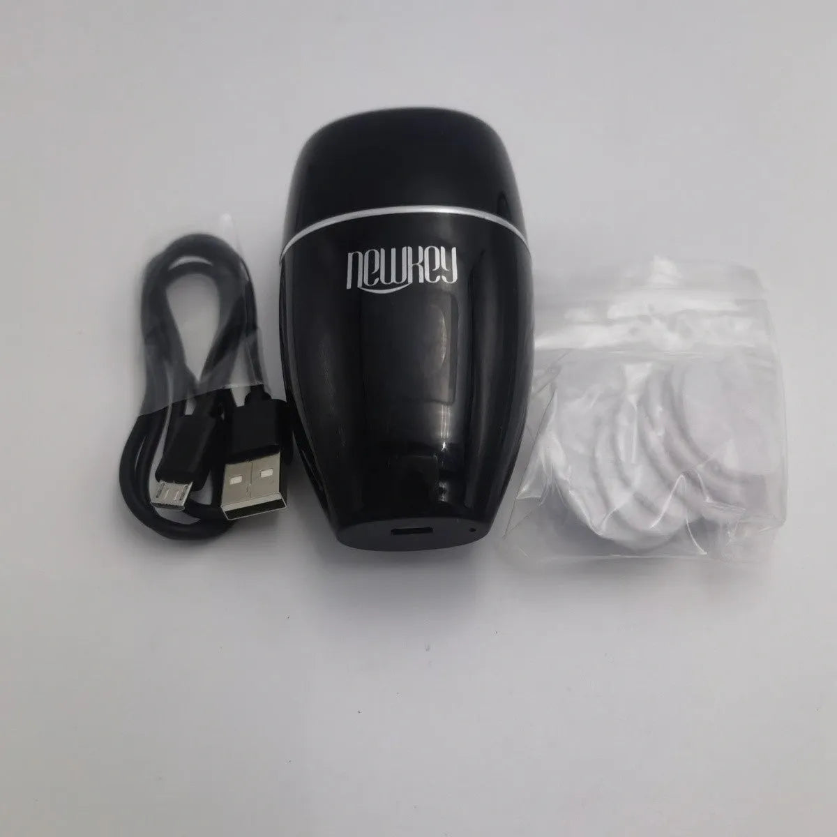 Black and white electric lip plumper device with USB charging cable on a plain background.