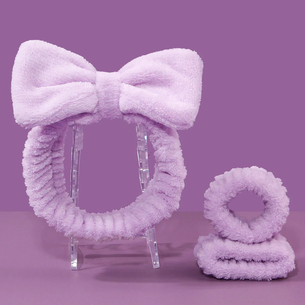 Facial brush with plastic handle and nylon bristles alongside coral fleece absorbent hair band in purple colour