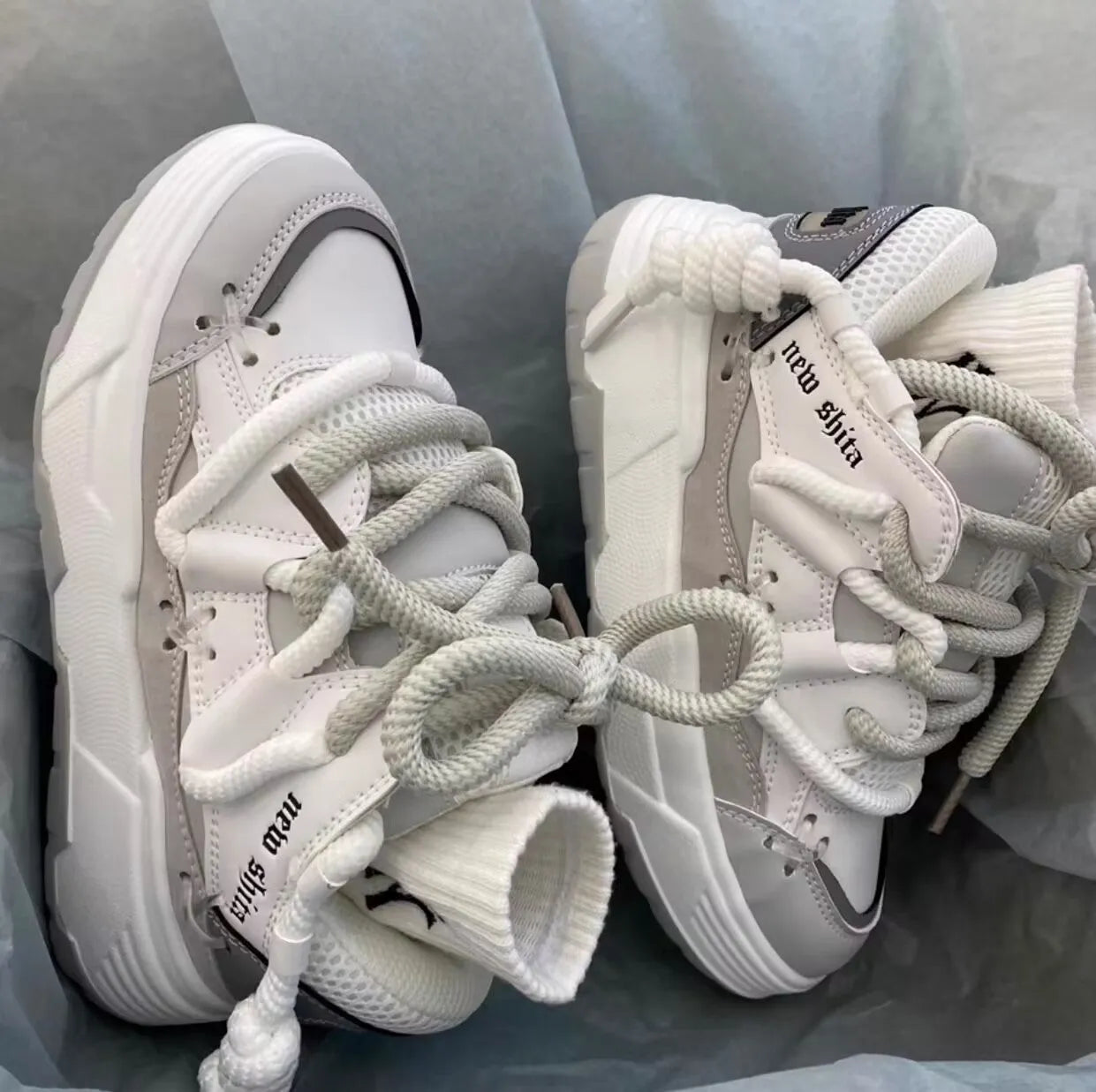 Grey retro clunky sneakers with thick rubber sole and lace-up front, shown on a white background.