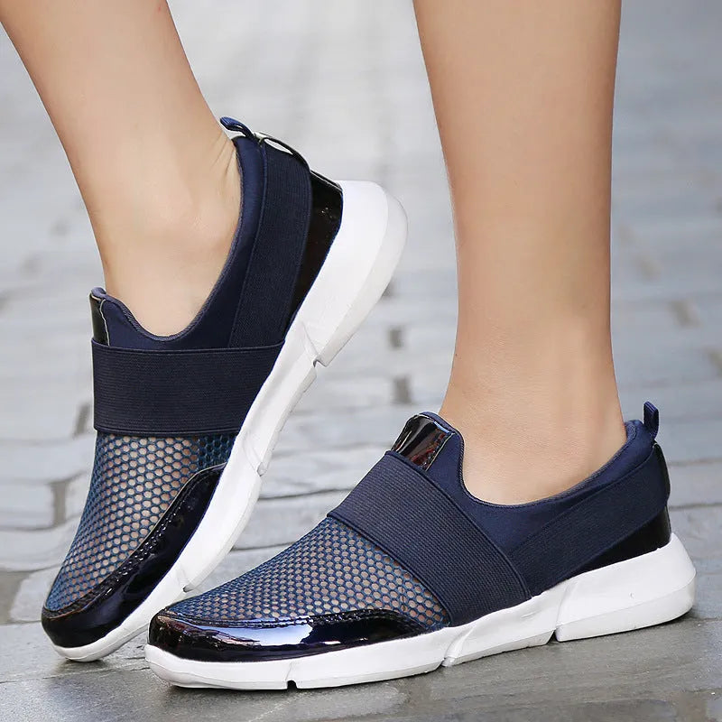 Low-cut blue women's casual sneakers with mesh upper on a hard floor surface.