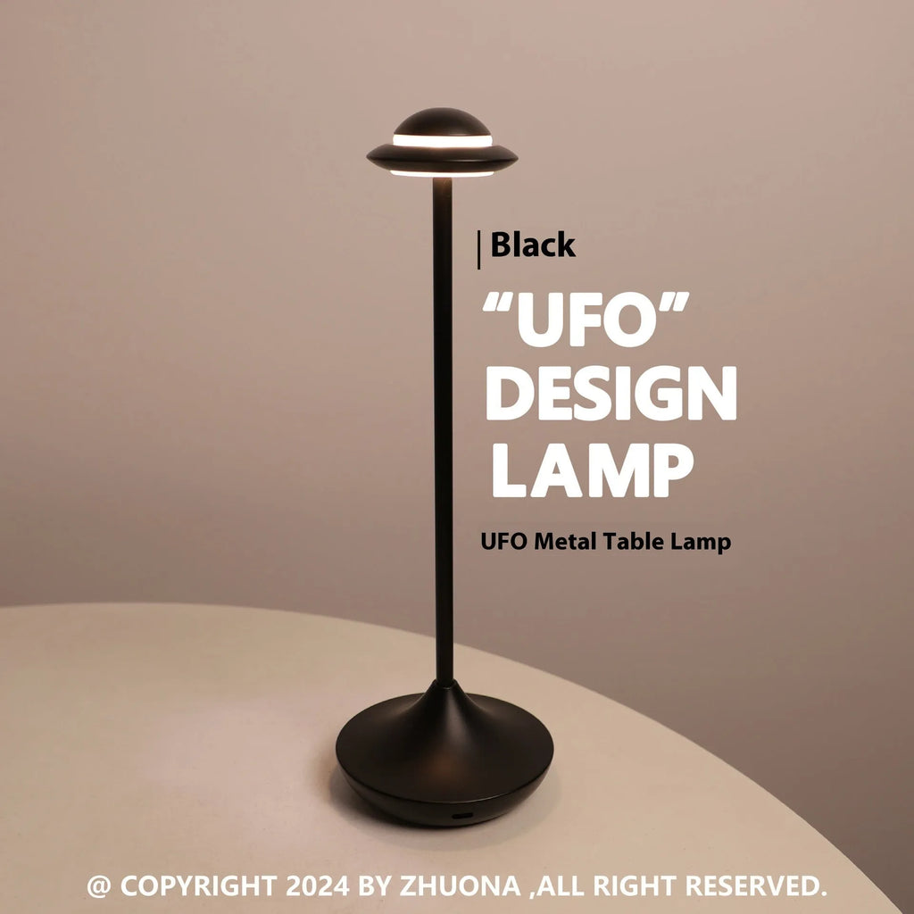 Creative metal UFO table lamp in black with touch dimming on a wooden desk.