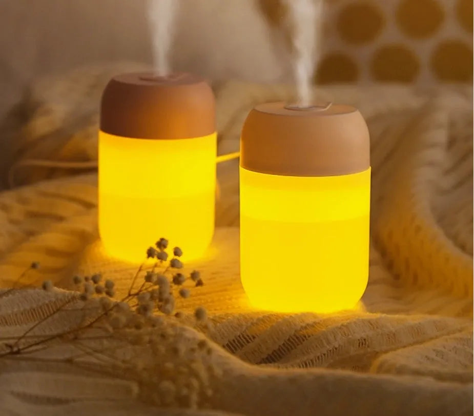 Small white cylindrical USB humidifier with aromatherapy function on a desk.
