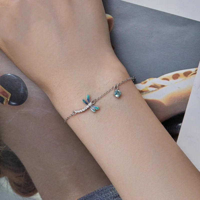 Sterling silver white gold plated dragonfly bracelet with dripping cubic zirconia stones on a light background