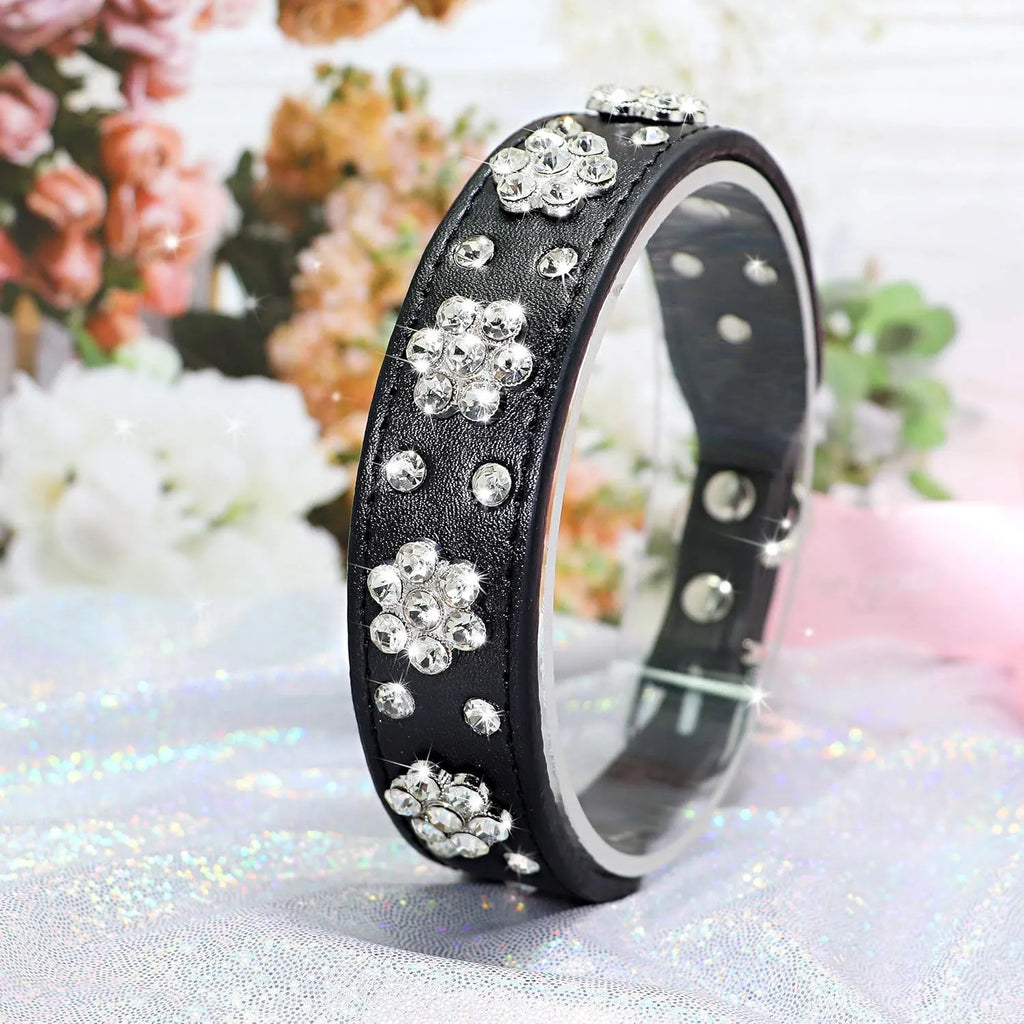 PU leather dog collar with rhinestone flower studs in black, showing metal D-ring and adjustable eyelets.