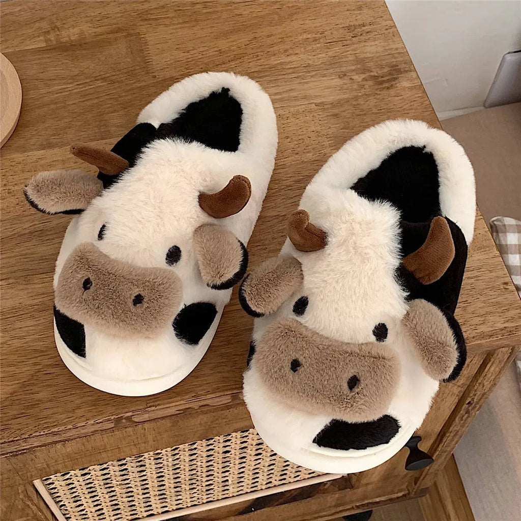 White cartoon cow plush house slippers for women with a non-slip textured sole.