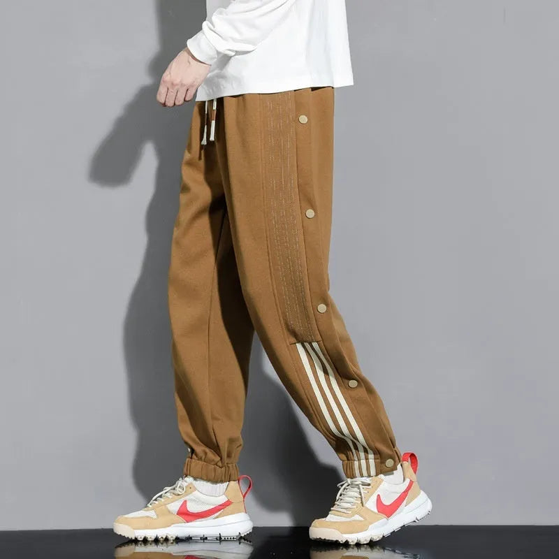 Men's black high-waist sweatpants with ankle-tied cuffs and a drawstring waist on a grey background.