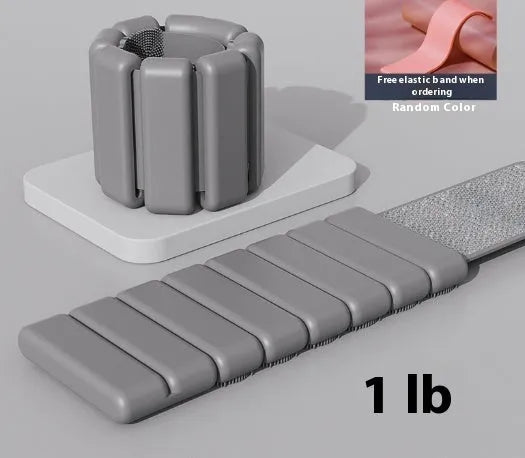 Adjustable black silicone wrist weight bracelet with a detached 2lb metallic weight on a grey background.