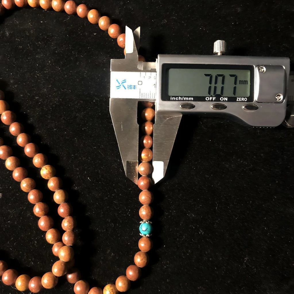 Handmade geometric bracelet with 108 smooth Lvzhu stone beads.