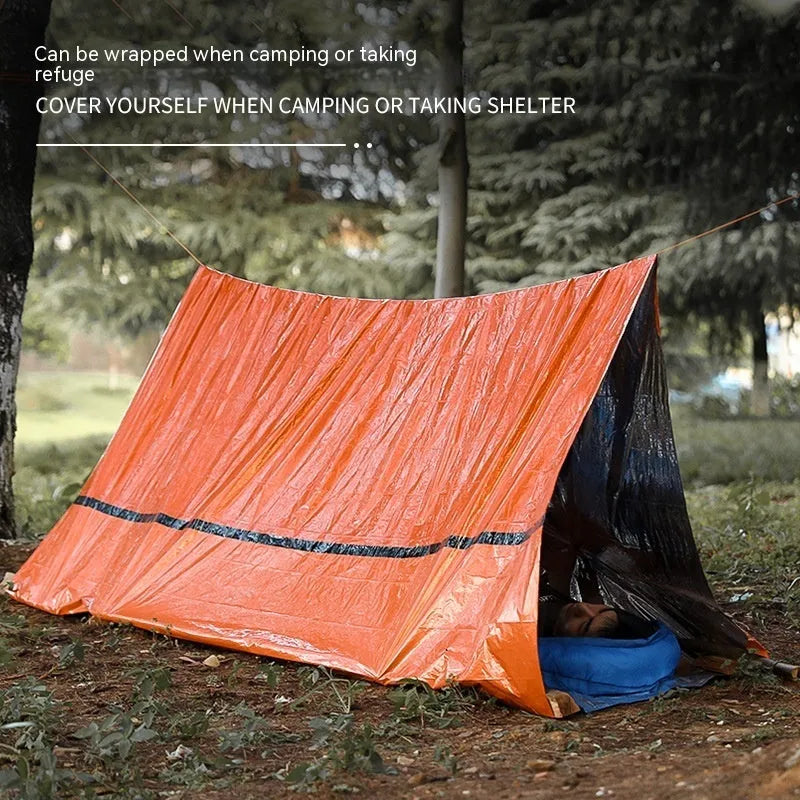 Orange emergency relief tent with sleeping bag and raincoat in temporary outdoor shelter setup