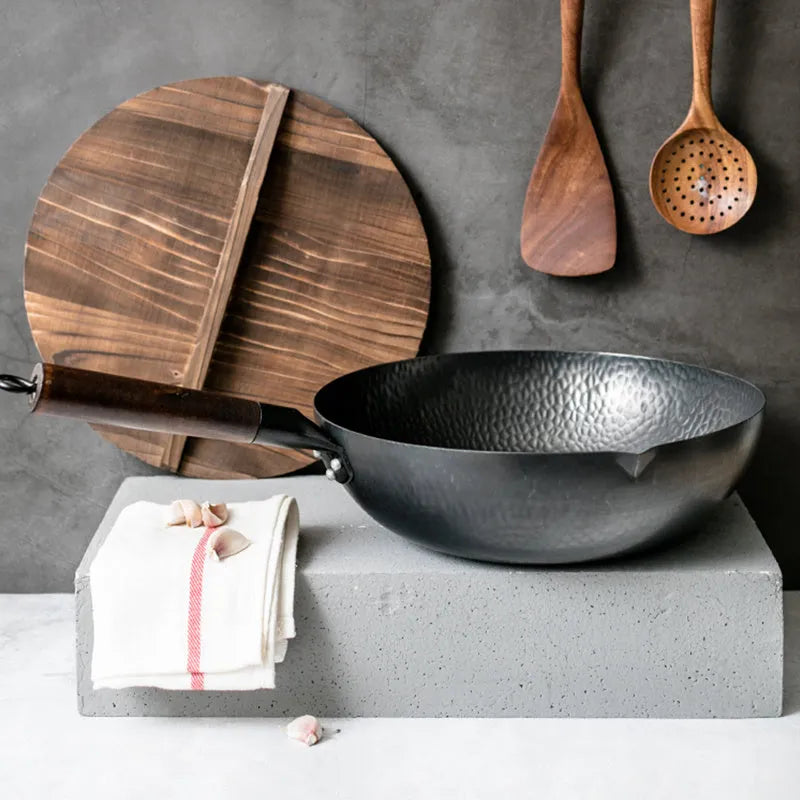 Traditional handmade iron wok pan with wooden handle and induction-compatible base