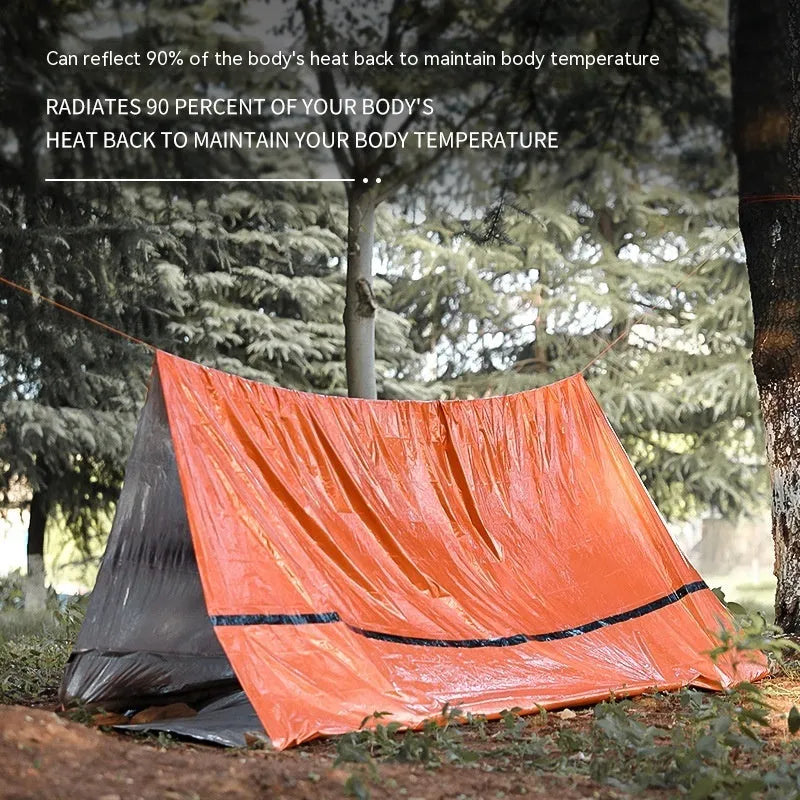 Orange emergency relief tent with sleeping bag and raincoat in temporary outdoor shelter setup