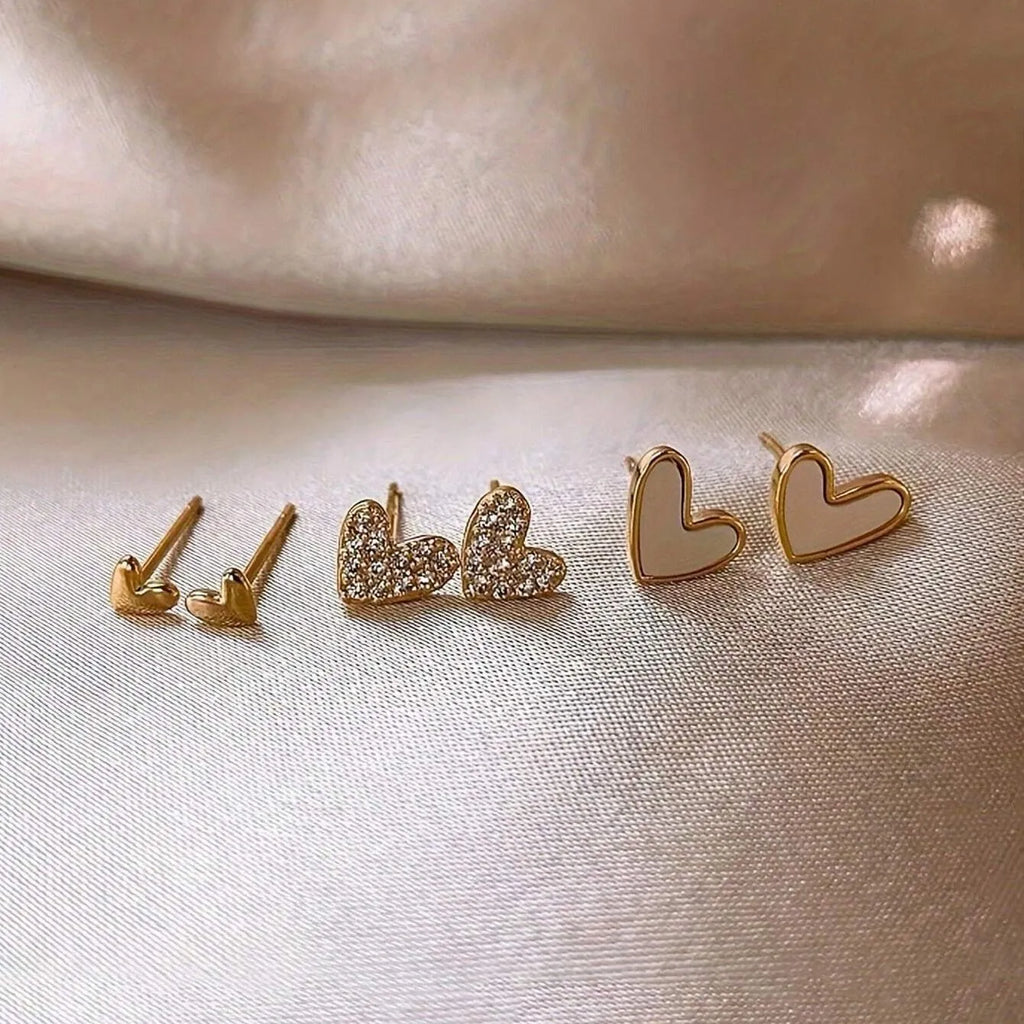Three pairs of women's heart-shaped alloy earrings in gold, black, white, and pink colours