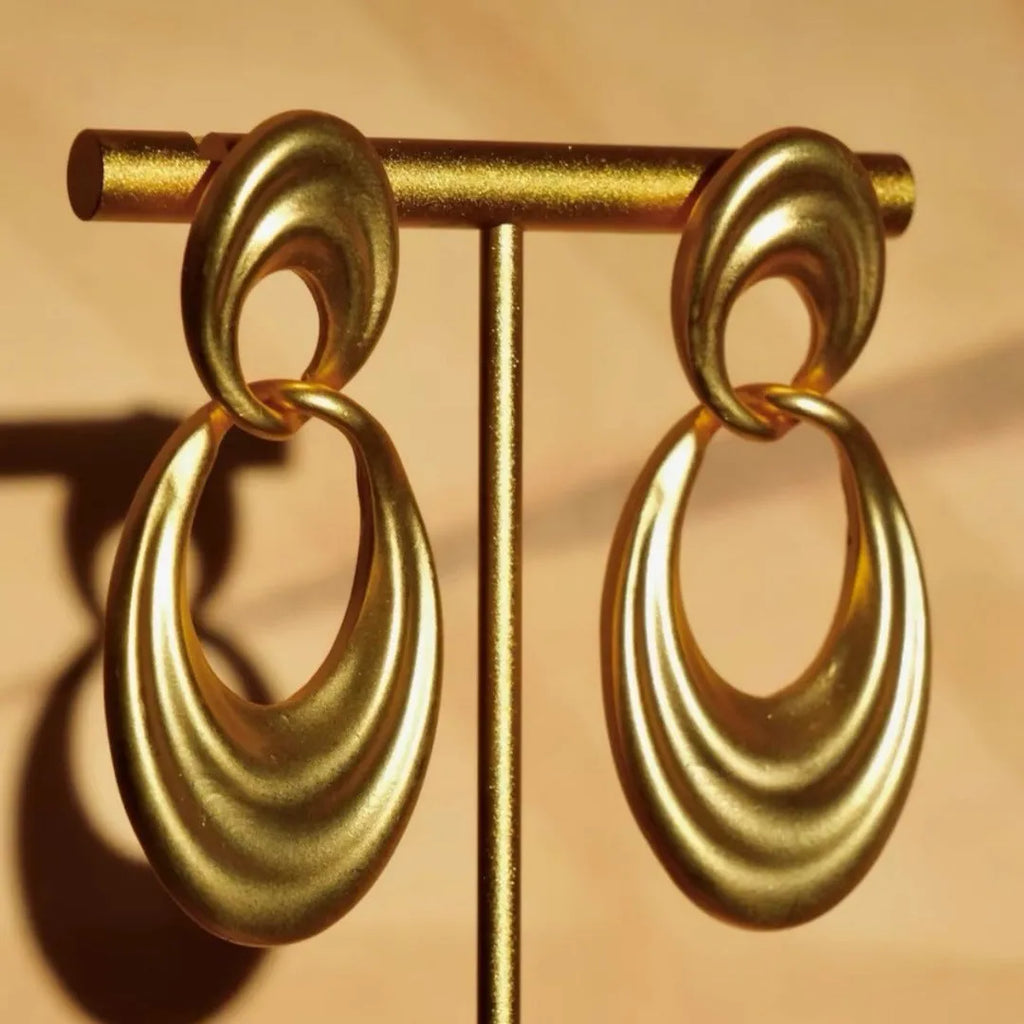 Pair of quicksand gold copper earrings showing a U-shaped design with a double circle detail.