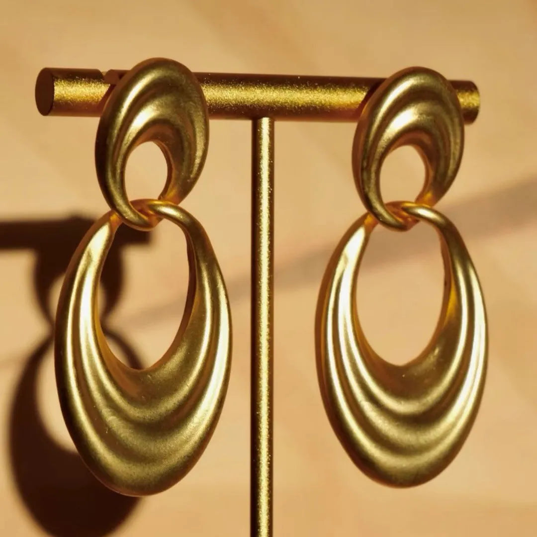 Pair of quicksand gold copper earrings showing a U-shaped design with a double circle detail.