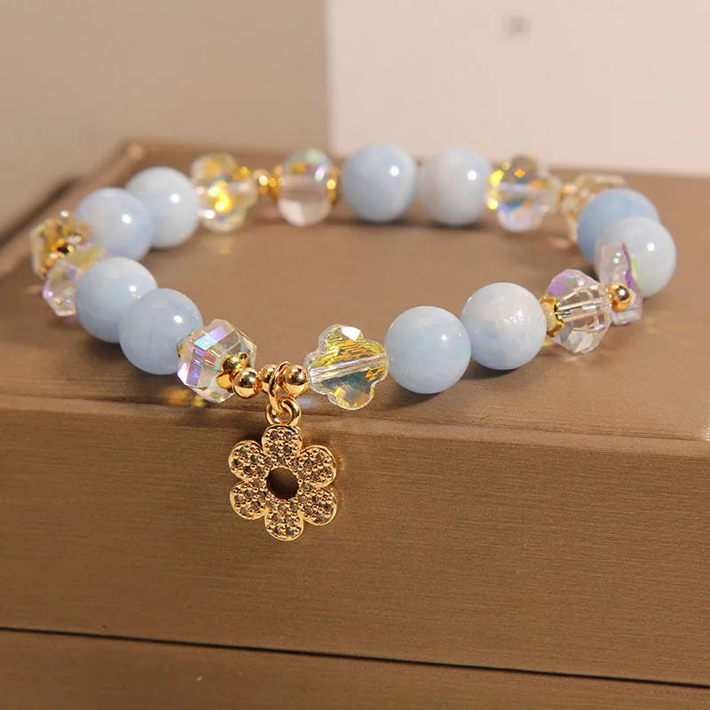 Women's aquamarine crystal bracelet featuring a four-leaf clover charm and pearl decorative elements.