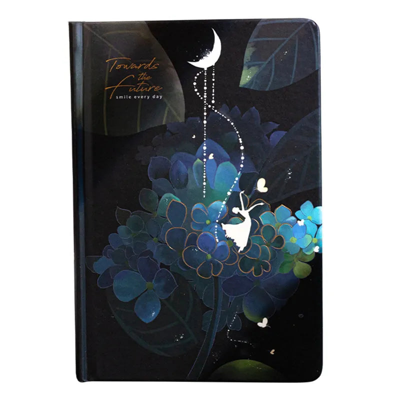 A5 notebook with luminous cover in deep blue, open to show lined pages with colour illustrations.