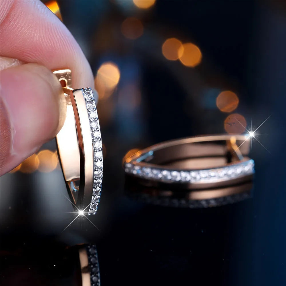 Close-up of women's geometric V-shaped clip-on earrings in champagne gold with white diamond details on a copper base.